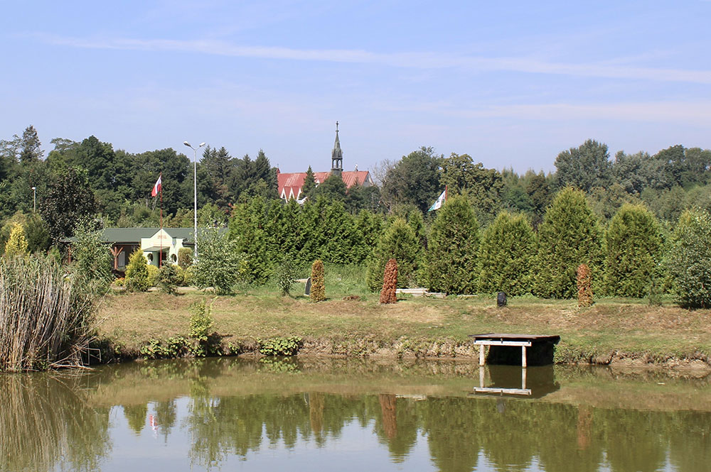 Widok na jezioro, w tle drzewa oraz wieża kościoła.